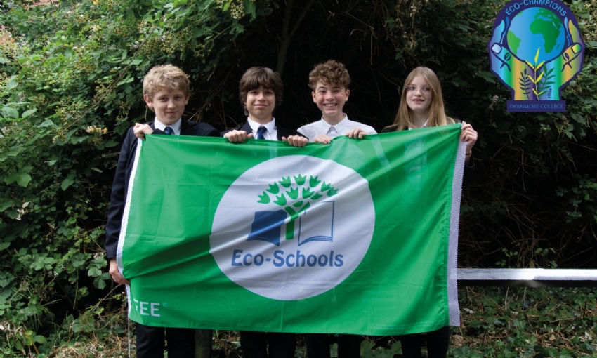 Image shows 4 pupils holding the Eco-Schools' green flag